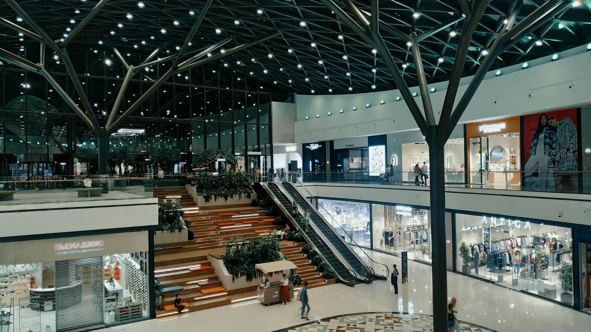 Explore a spacious and contemporary shopping mall featuring trendy shops, lush greenery, and stylish architecture.